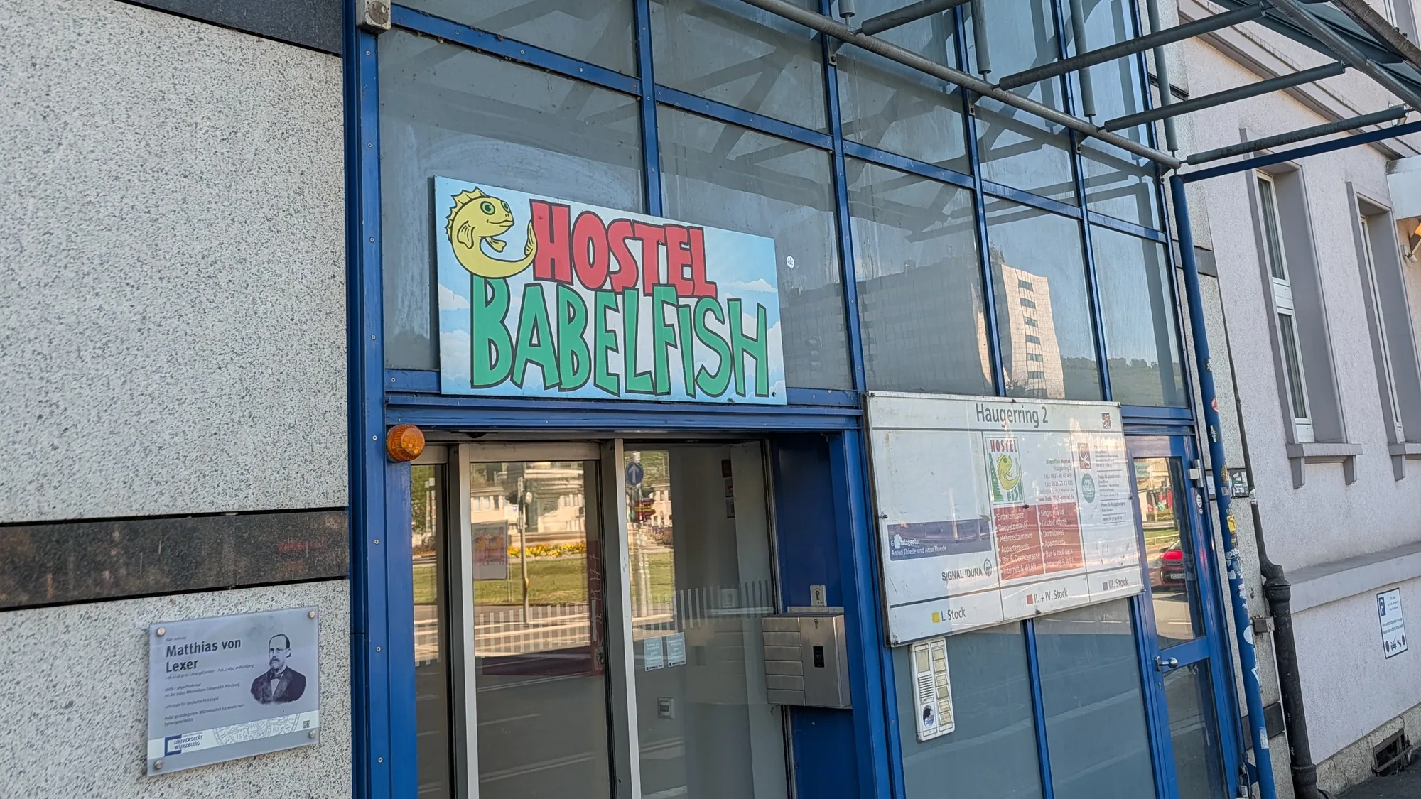 Der Eingang des Hostel Babelfish am Haugerring mit Glasvordach und dem Aushang der Hausnummer 2