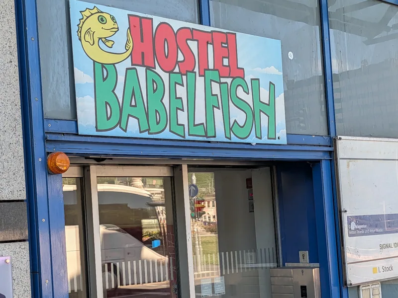 Das gemalte Schild des Hostel Babelfish über der Eingangstür, ein gelber Fisch neben dem Schriftzug