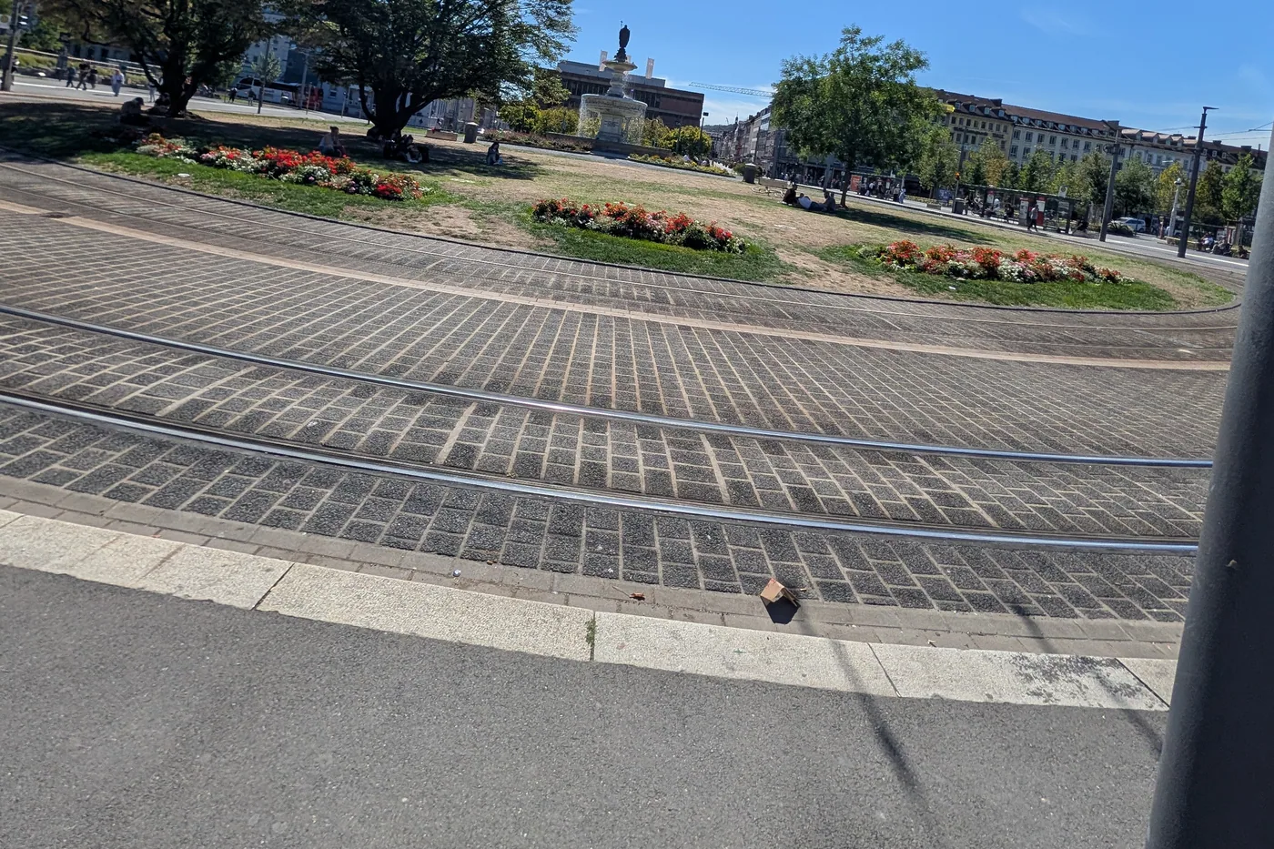 Der Bahnhofsvorplatz mit den Strassenbahngleisen, dahinter die Gruenflaeche mit dem Kiliansbrunnen