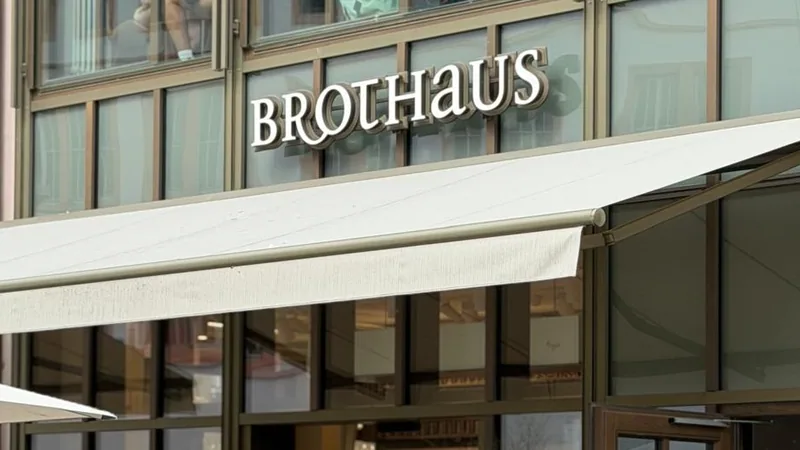 Der Schriftzug BROTHAUS in weißen Buchstaben über der Glasfassade am Würzburger Marktplatz, darunter die ausgefahrene Markise