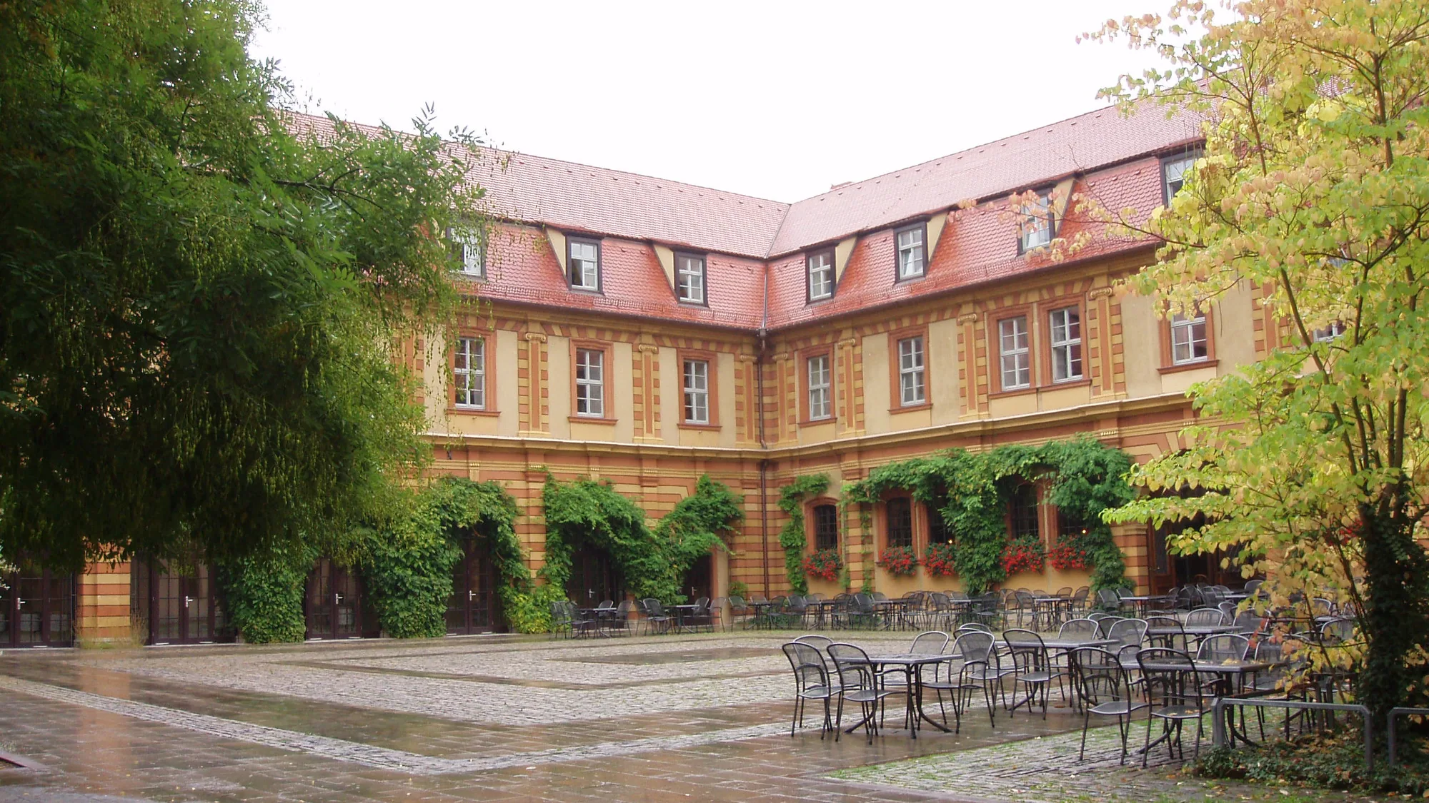 Innenhof des Bürgerspitals mit Arkaden und Bäumen, davor leere Tische der Weinstube
