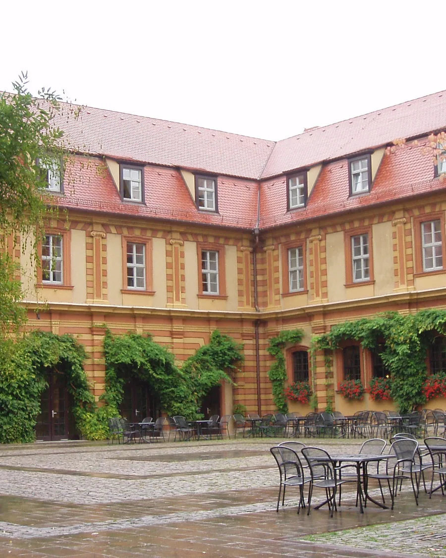Innenhof des Bürgerspitals mit Arkaden und Bäumen, davor leere Tische der Weinstube