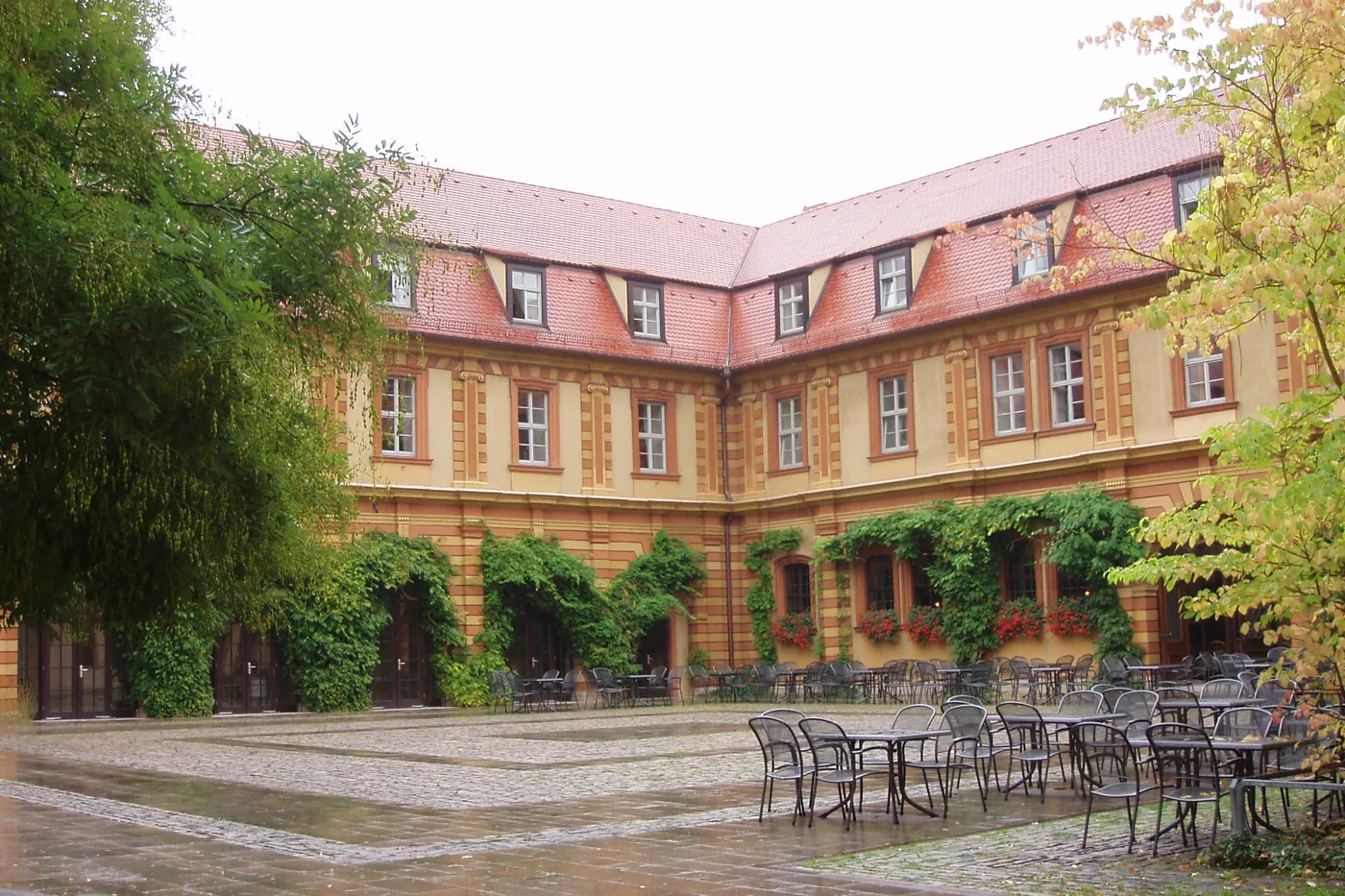 Innenhof des Bürgerspitals mit Arkaden und Bäumen, davor leere Tische der Weinstube