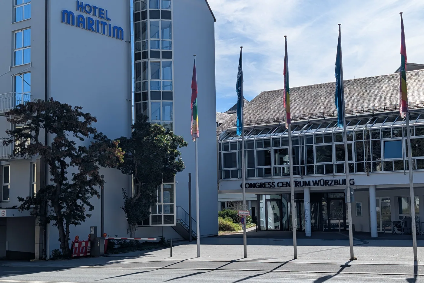 Der Haupteingang des Congress Centrums Würzburg mit den Fahnenmasten davor, links das Hotel Maritim