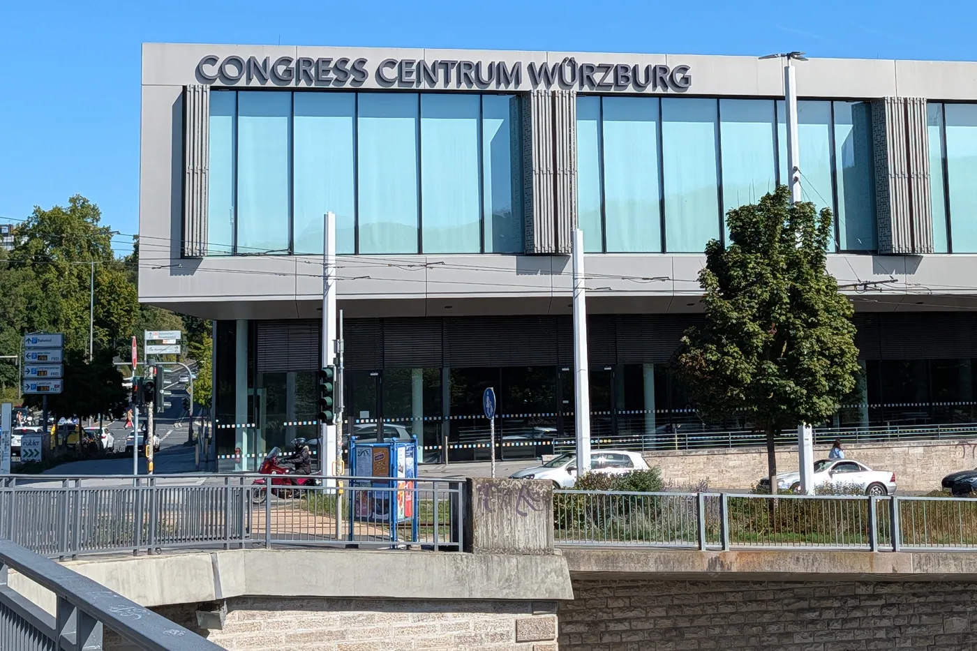 Die auskragende Glasfassade des Congress Centrums über der Straßenbahnstrecke, links das Parkleitsystem