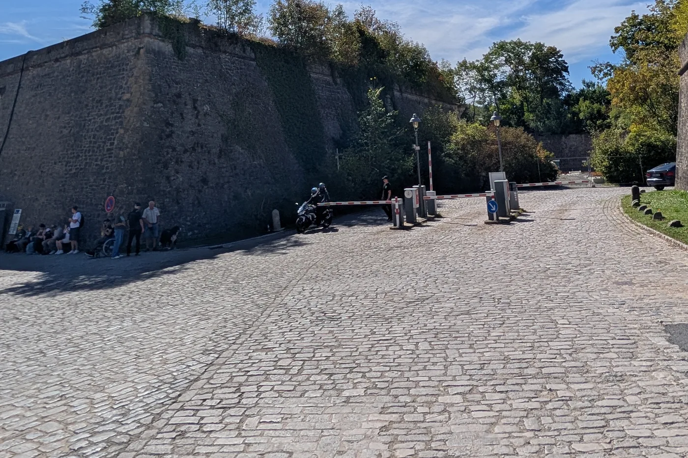 Die Zufahrt zur Festung mit Schranke und Kassenautomat, links die Bastionsmauer