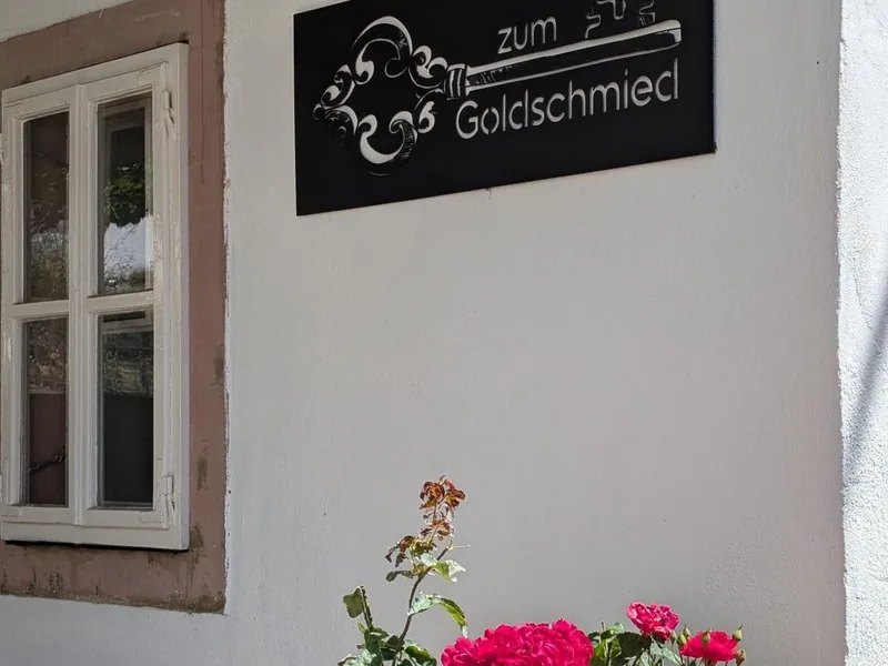 Das Eingangsschild des Ferienhauses Zum Goldschmied mit Rosen