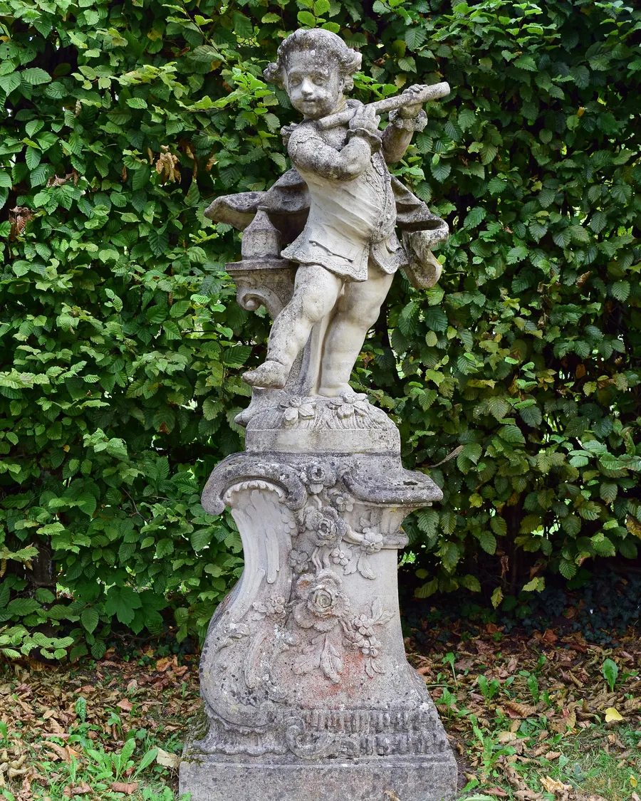 Puttenfigur aus Sandstein vor einer Hecke im Hofgarten Veitshöchheim