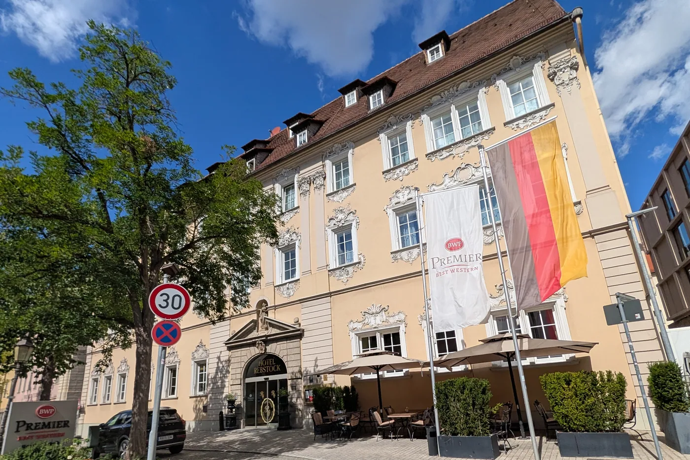 Das Hotel Rebstock in der Würzburger Neubaustraße, Rokokofassade mit Stuckdekor über drei Geschossen, davor die Terrasse mit Sonnenschirmen