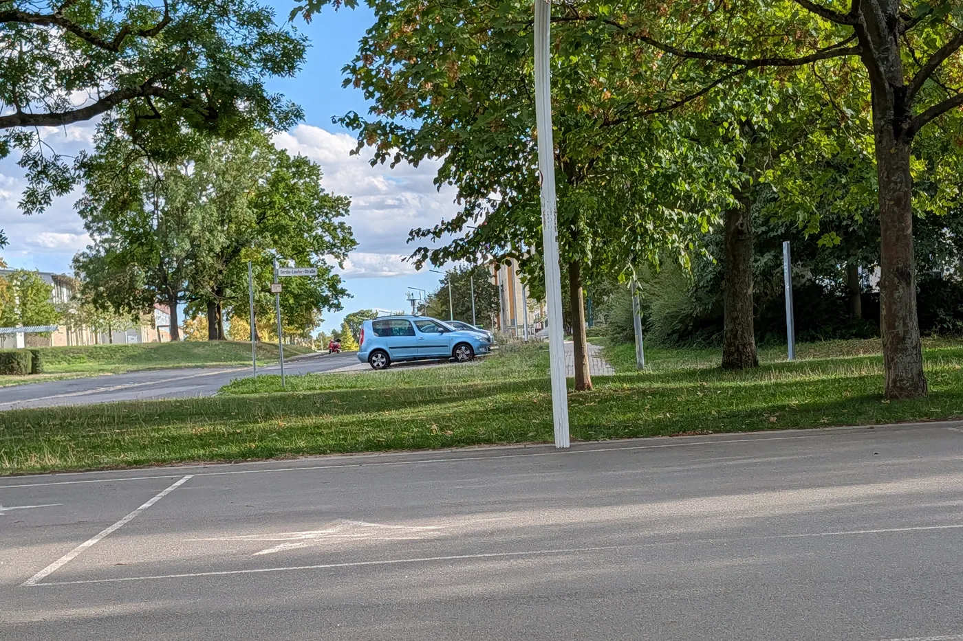 Ein Basketballkorb am Rand des Spielfelds am Hubland, dahinter eine Straße und Bäume