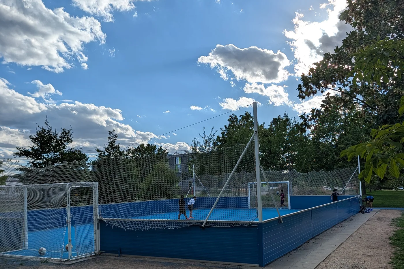 Ein blau umbandeter Soccer-Court mit Fangnetzen am Hubland, auf dem Feld spielen mehrere Jugendliche