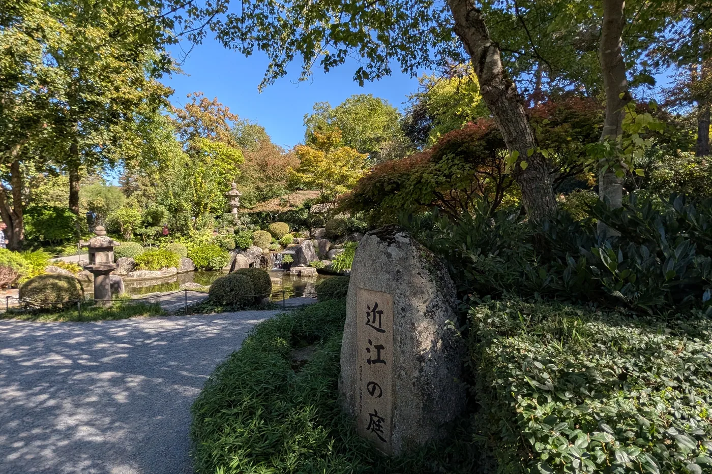 Der Gedenkstein mit den Schriftzeichen für Ōmi no niwa, dahinter der Teich mit Steinlaternen