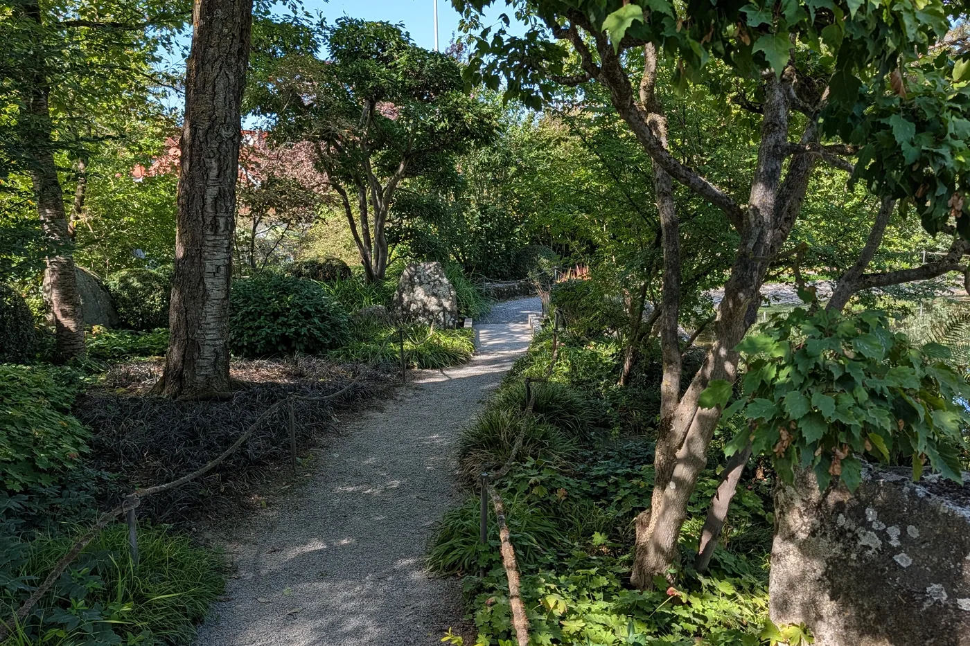 Der Weg durch den Japanischen Garten, rechts eine Tafel mit einem japanischen Sinnspruch