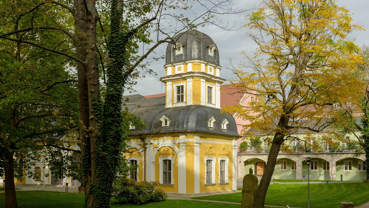 Gartenpavillon des Juliusspitals mit Zwiebelhaube, umgeben von Bäumen im Herbst