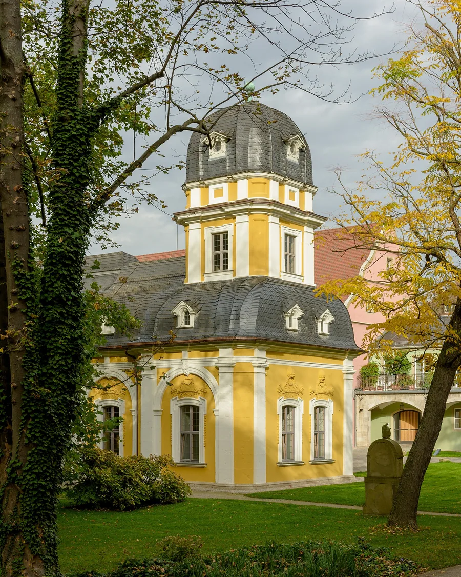 Gartenpavillon des Juliusspitals mit Zwiebelhaube, umgeben von Bäumen im Herbst