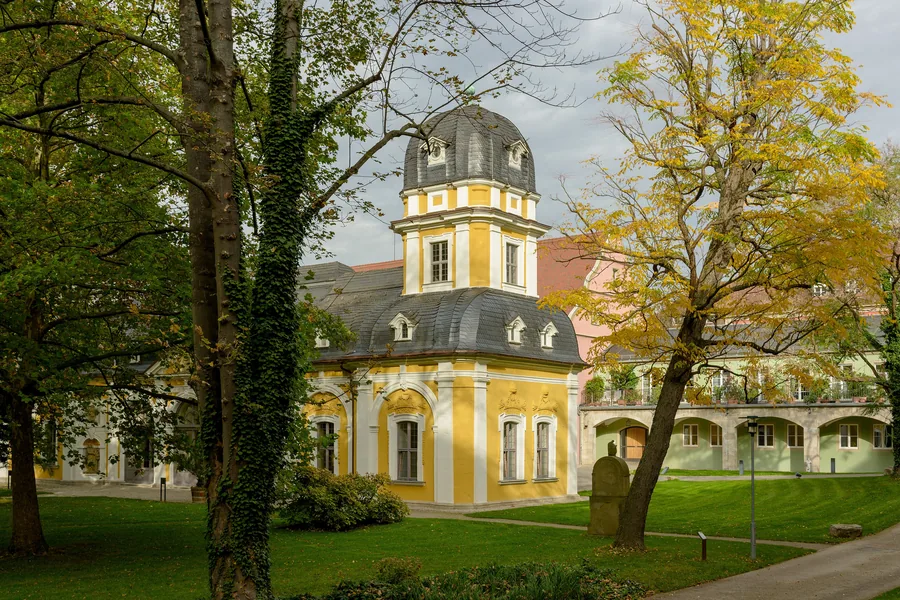 Gartenpavillon des Juliusspitals mit Zwiebelhaube, umgeben von Bäumen im Herbst