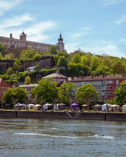 Der Kunsthandwerkermarkt an der Leonhard-Frank-Promenade, vom anderen Mainufer aus gesehen, darüber die Festung Marienberg