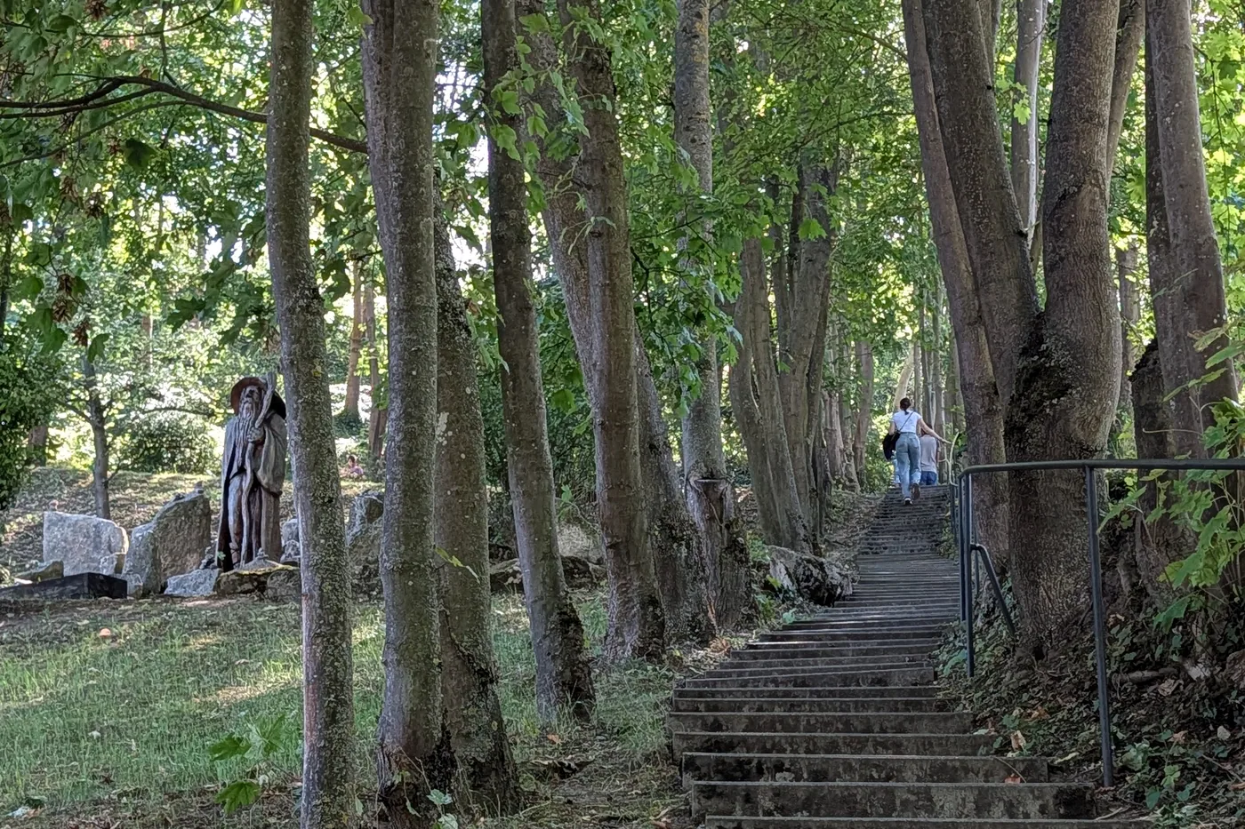 Die Treppe im Waldstück des Parks, daneben die geschnitzte Holzfigur
