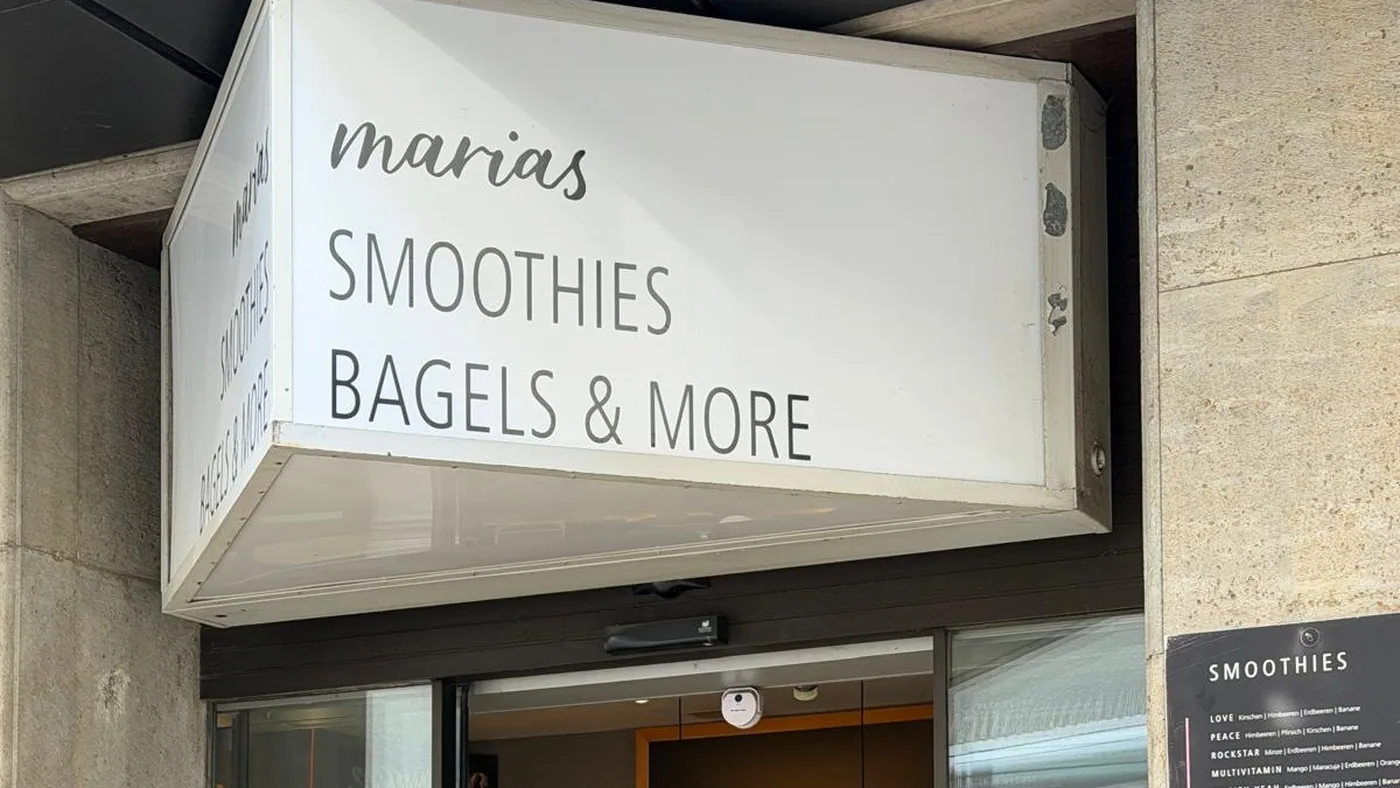 Der weiße Leuchtkasten von marias Smoothies, Bagels & More über dem Eingang in der Wilhelmstraße, rechts die Tafel mit den Smoothie-Sorten