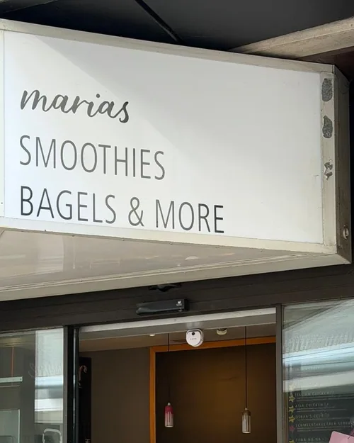 Der weiße Leuchtkasten von marias Smoothies, Bagels & More über dem Eingang in der Wilhelmstraße, rechts die Tafel mit den Smoothie-Sorten
