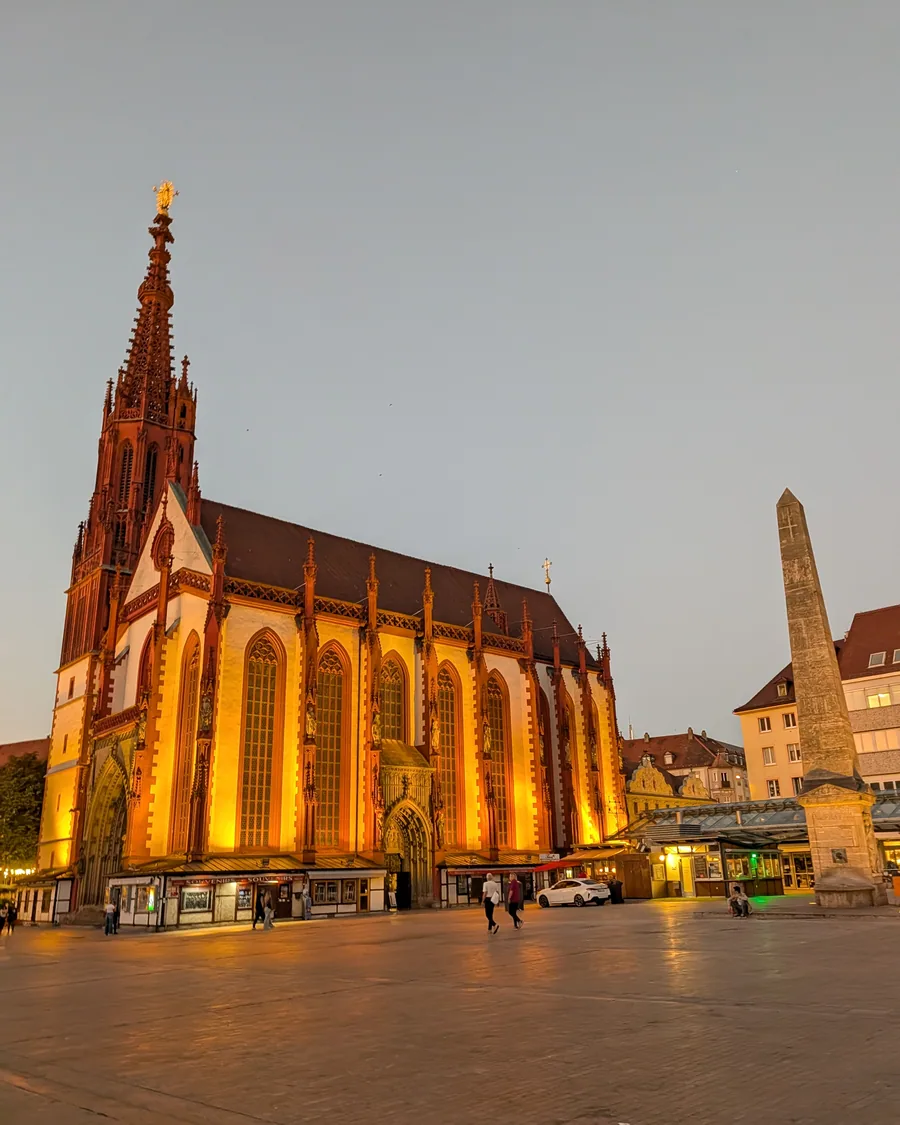 Die angestrahlte Marienkapelle am Würzburger Marktplatz in der Abenddämmerung, rechts der Obelisk