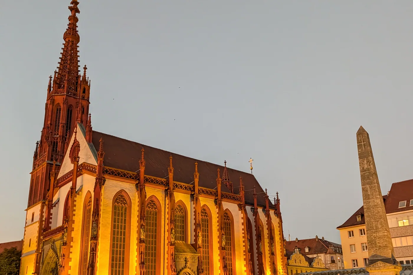 Die angestrahlte Marienkapelle am Würzburger Marktplatz in der Abenddämmerung, rechts der Obelisk