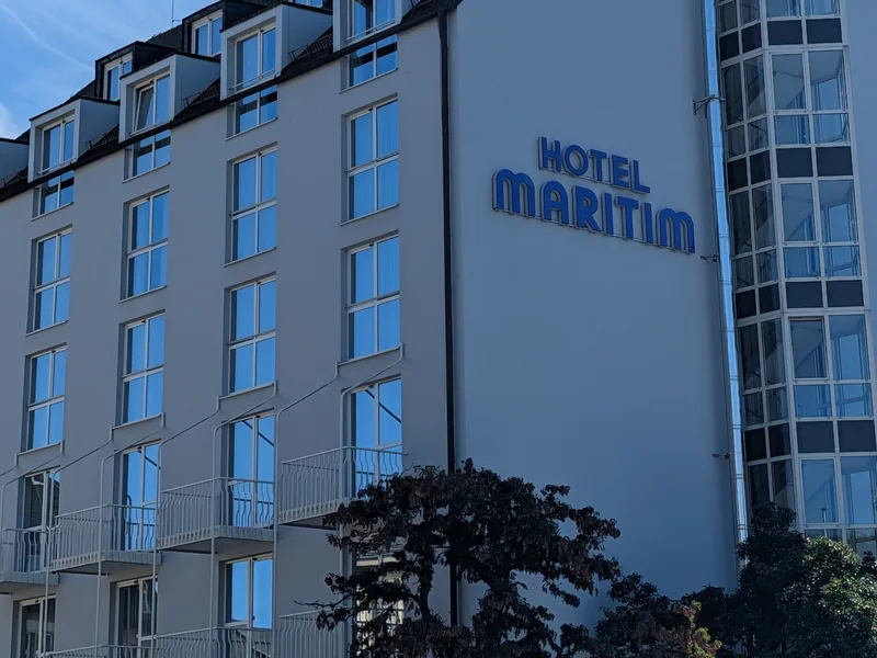 Der blaue Schriftzug Hotel Maritim an der Giebelseite, daneben der verglaste Treppenturm