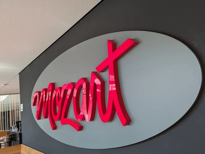 Der rote Schriftzug Mozart auf einem grauen Oval an der dunklen Wand des Cafés