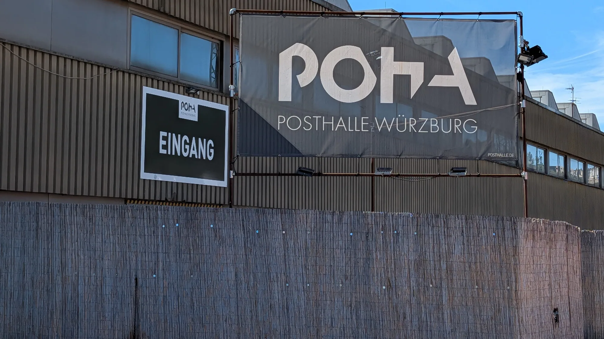 Das Banner mit dem POHA-Logo an der Wellblechfassade der Posthalle, links das Eingangsschild