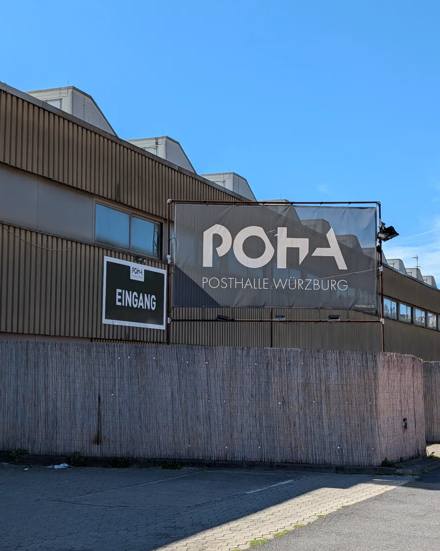 Das Banner mit dem POHA-Logo an der Wellblechfassade der Posthalle, links das Eingangsschild