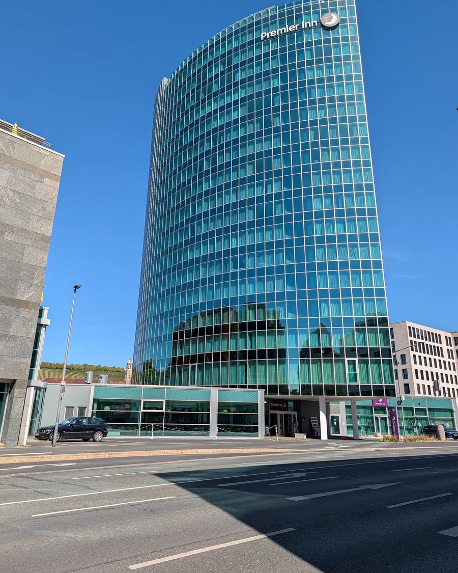 Der gläserne Turm des Premier Inn an der Schweinfurter Straße, links im Hintergrund die Weinberge