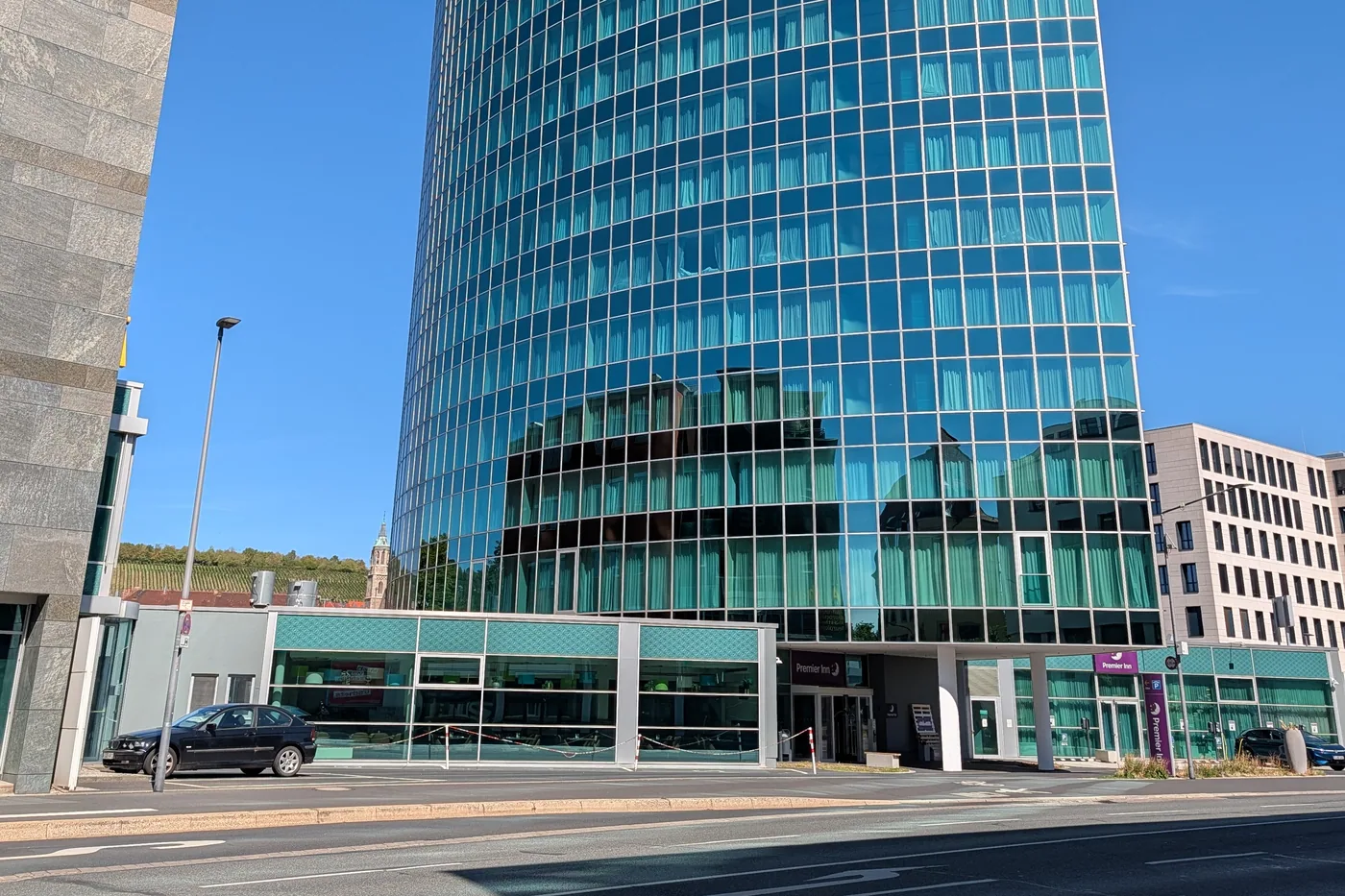 Der gläserne Turm des Premier Inn an der Schweinfurter Straße, links im Hintergrund die Weinberge