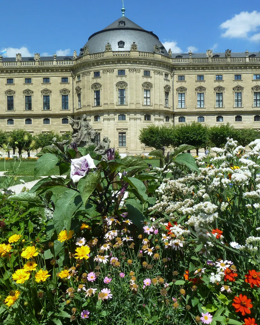 Die Residenz hinter einem blühenden Staudenbeet im Hofgarten