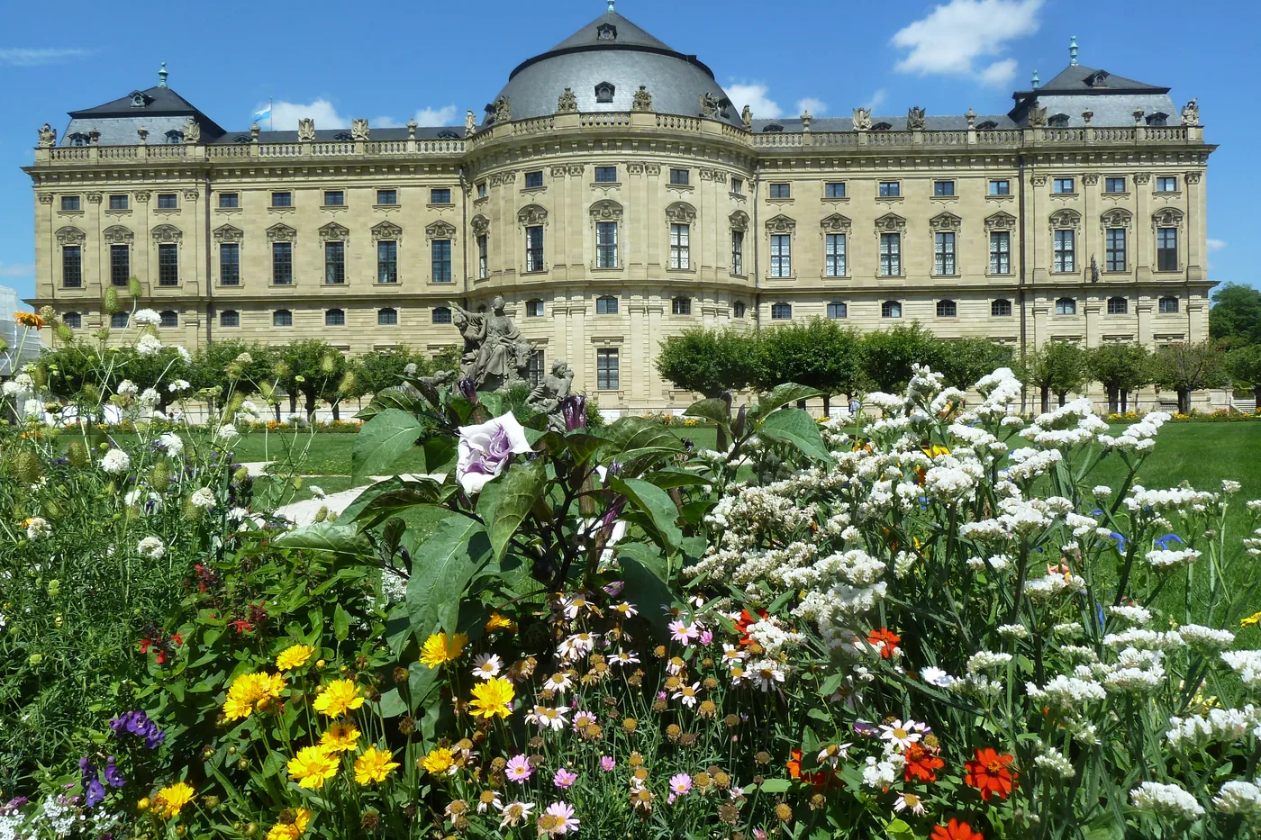 Die Residenz hinter einem blühenden Staudenbeet im Hofgarten