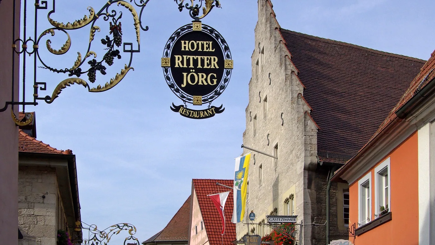 Gasse in Sommerhausen mit Fachwerkhäusern und einem schmiedeeisernen Wirtshausschild