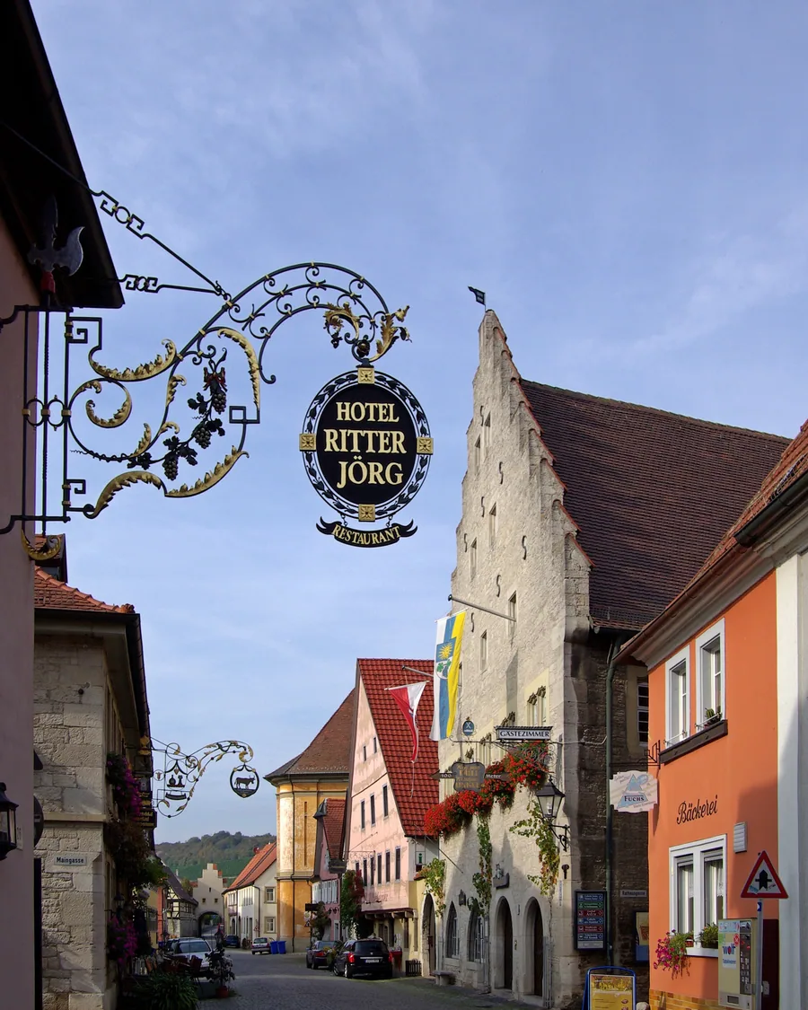Gasse in Sommerhausen mit Fachwerkhäusern und einem schmiedeeisernen Wirtshausschild