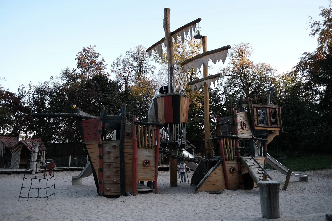Kletterschiff aus Holz auf dem Piratenspielplatz, daneben ein Sandbereich