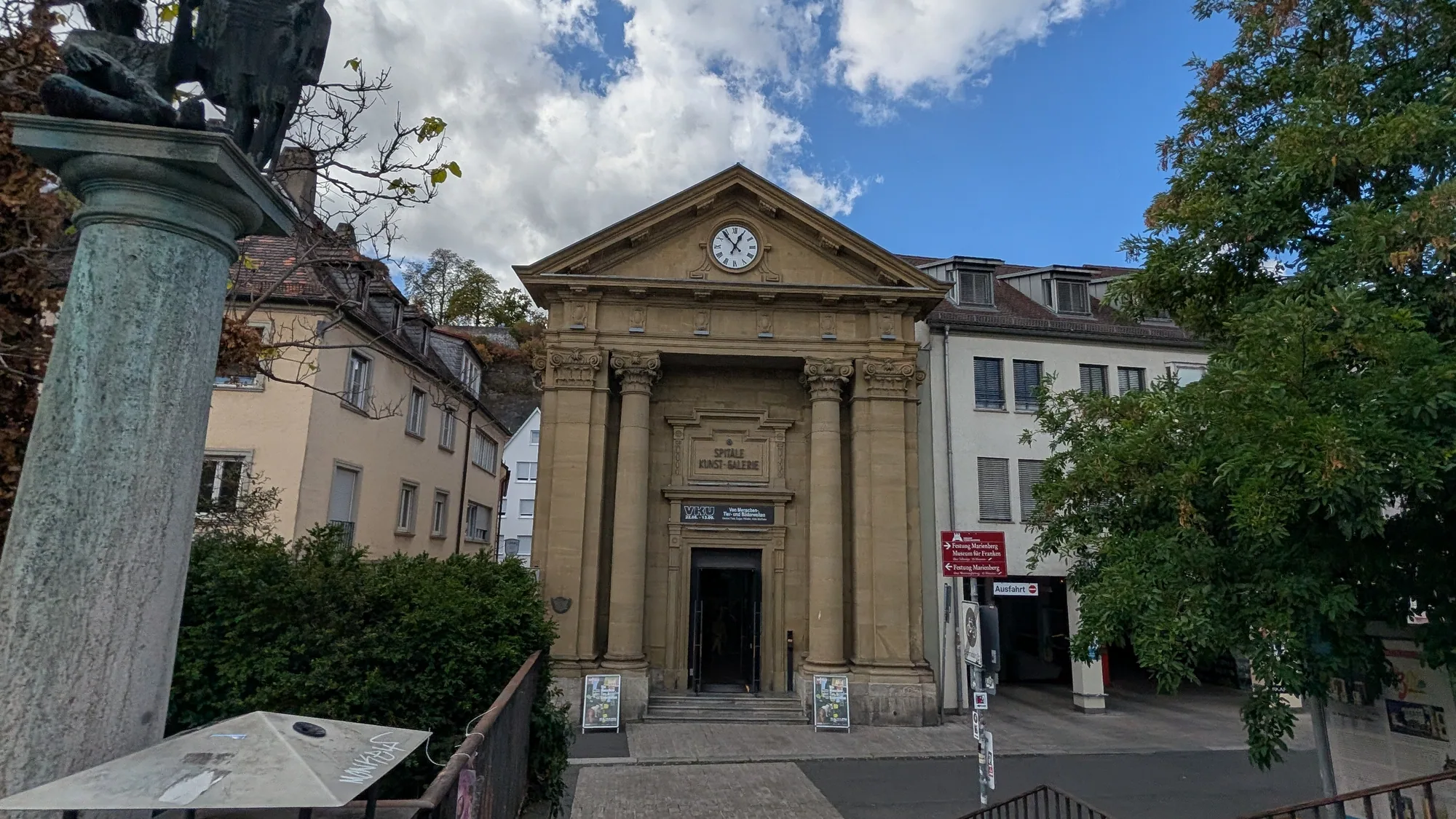Das Spitäle am Mainufer mit Säulenportal und Uhr, davor die Skulptur auf der Säule