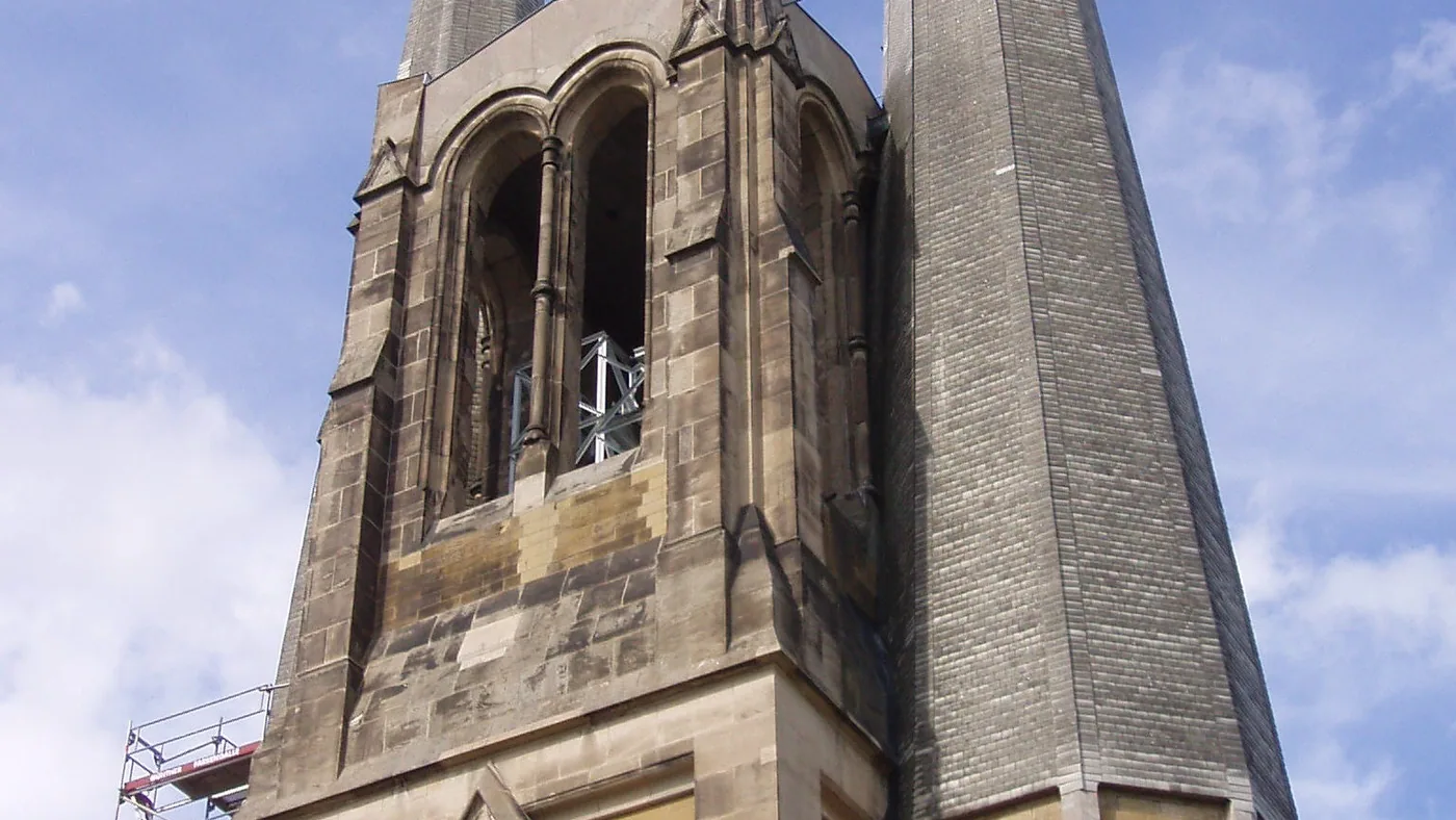 Die beiden Türme von St. Johannis vor blauem Himmel, der eine mit spitzem Helm, der andere mit Uhr