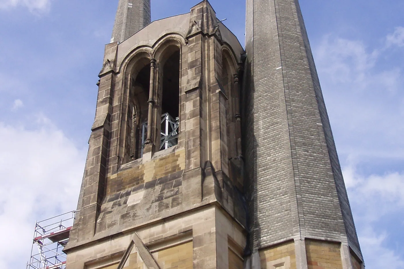 Die beiden Türme von St. Johannis vor blauem Himmel, der eine mit spitzem Helm, der andere mit Uhr