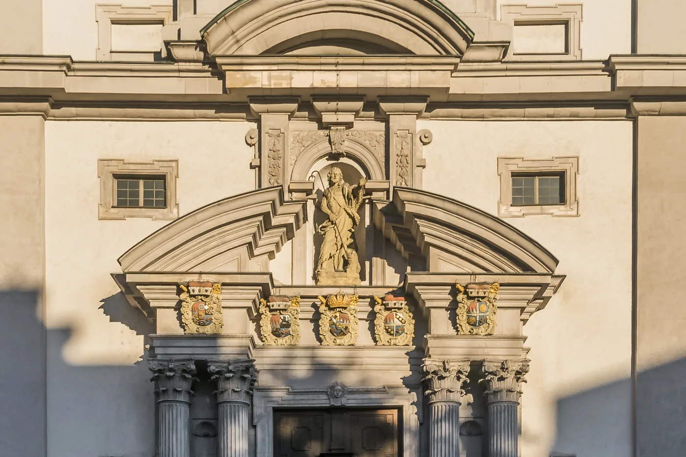 Die Barockfassade von Stift Haug mit Figurennischen und Säulenportal, von der Straße aus gesehen