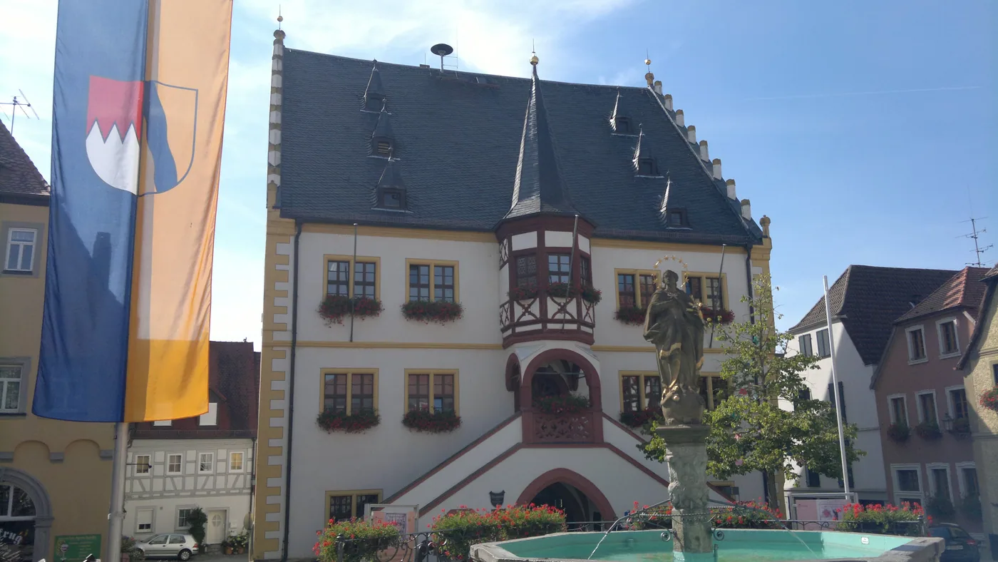 Das Rathaus von Volkach am Marktplatz, davor Brunnen und Fahne