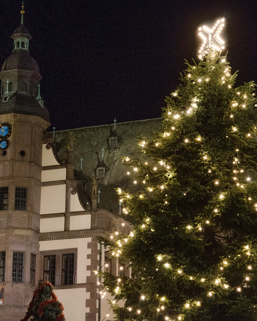 Das Alte Rathaus in Schweinfurt am Abend, davor der beleuchtete Christbaum des Weihnachtsmarkts