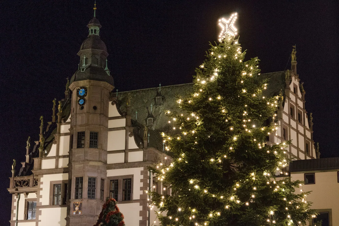 Das Alte Rathaus in Schweinfurt am Abend, davor der beleuchtete Christbaum des Weihnachtsmarkts