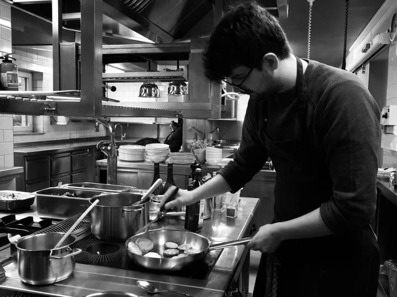 Der Küchenchef am Herd zwischen Töpfen und Pfannen, Schwarzweißaufnahme