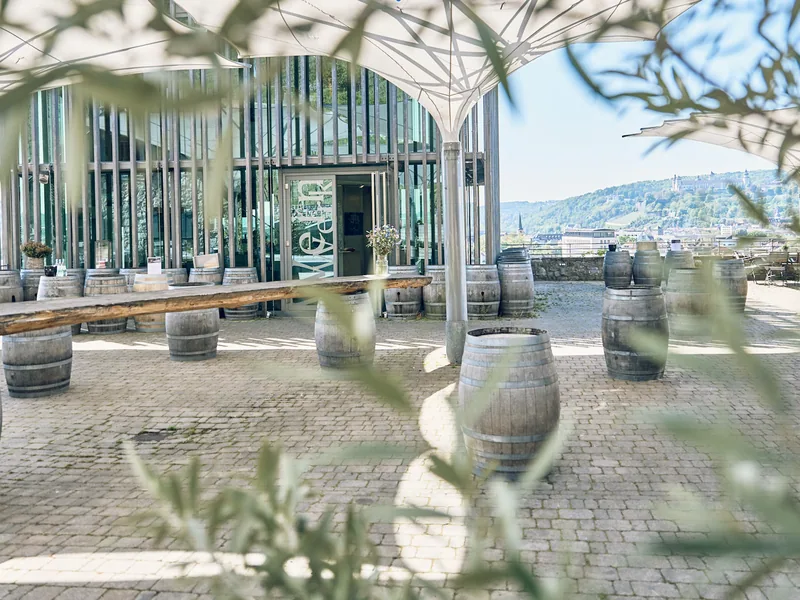 Die Terrasse am Weingut am Stein mit Weinfässern als Stehtischen, dahinter die Stadt und die Festung Marienberg