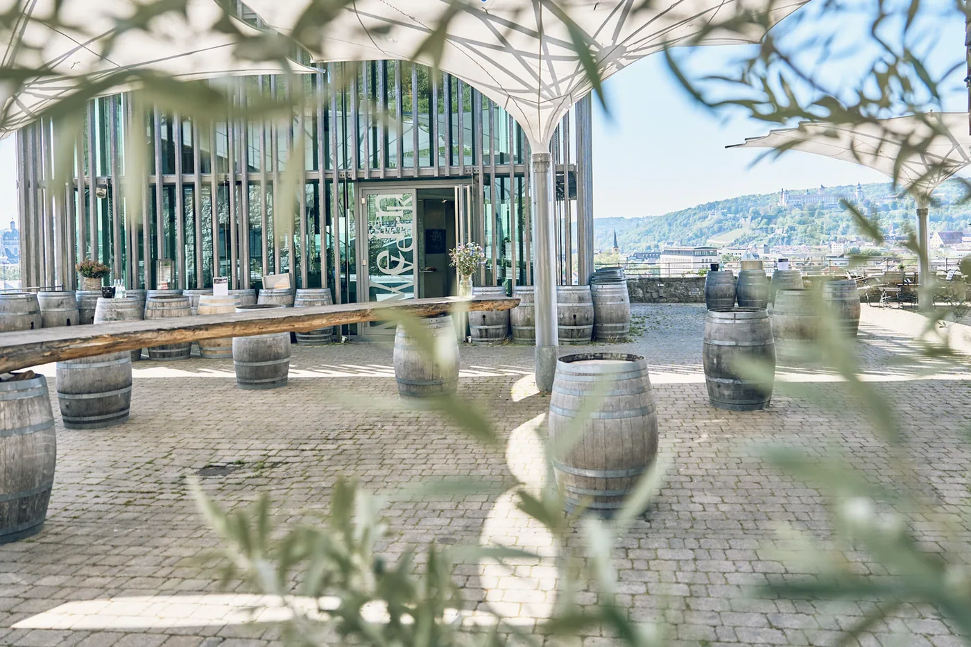 Die Terrasse am Weingut am Stein mit Weinfässern als Stehtischen, dahinter die Stadt und die Festung Marienberg